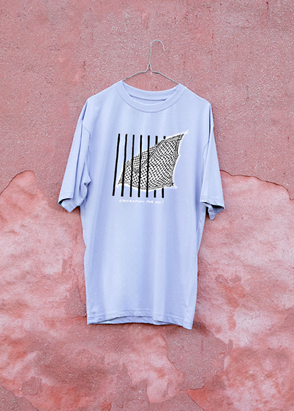 A light purple T-shirt hangs on a hook against a textured, faded pink wall. The shirt features a black and white abstract graphic design of a wave with vertical lines.